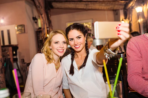 Young beautiful women with cocktails in bar taking selfie — Stok fotoğraf