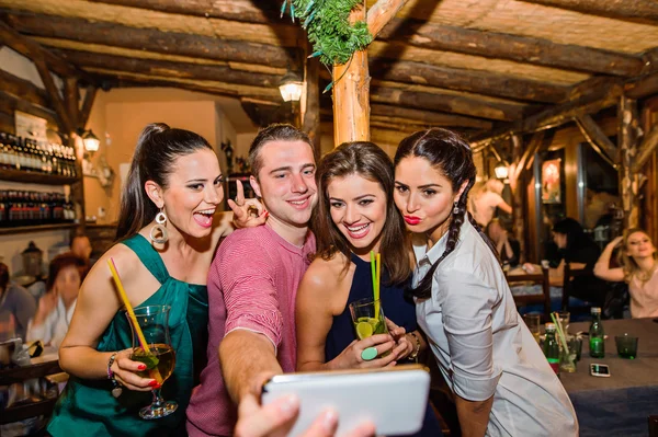 Молодые красивые люди с коктейлями в баре делают селфи — стоковое фото