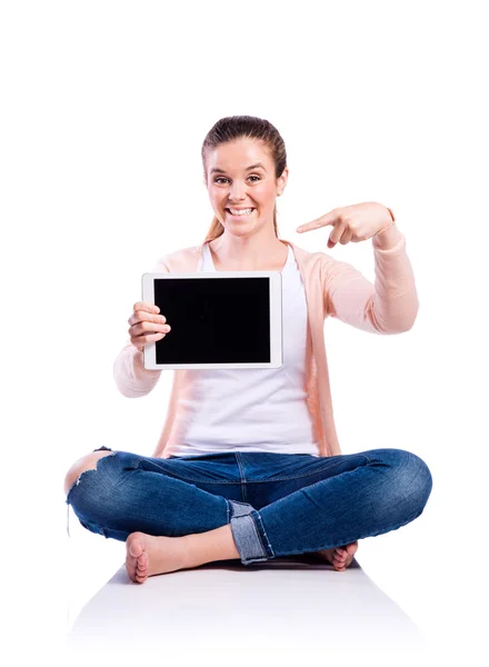 Vrouw met tablet zittend op de vloer, studio opname, geïsoleerd — Stockfoto