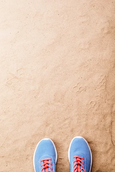 Sapatos esportivos azuis colocados na praia de areia, tiro estúdio — Fotografia de Stock