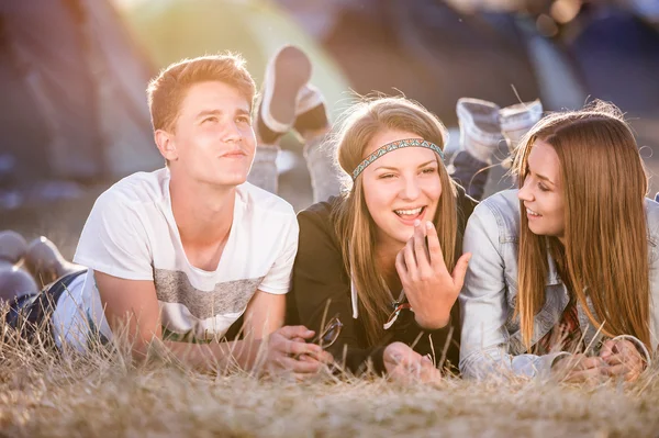 Teenagers lying on the ground in front of tents — Stock Photo, Image