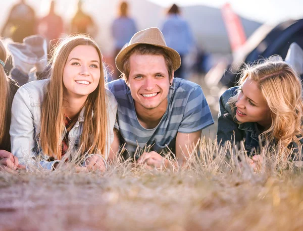 Teenagers lying on the ground in front of tents — Stock Photo, Image