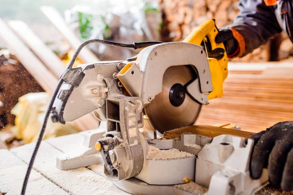 Zimmermannsarbeit. Mann sägt Bohlen mit Kreissäge. — Stockfoto