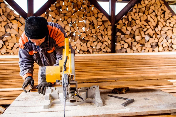 Zimmermannsarbeit. Mann sägt Bohlen mit Kreissäge. — Stockfoto