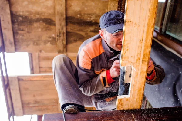 Człowiek, szlifowanie deski z drewna do budowy domu. — Zdjęcie stockowe