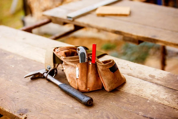 Borsa da falegnami con cintura piena di attrezzi, tavolo in legno — Foto Stock