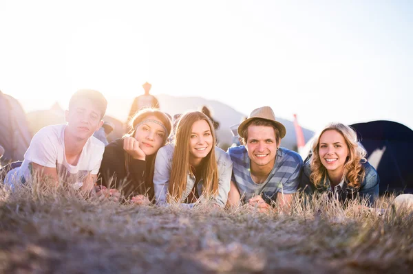 Teenagers lying on the ground in front of tents — Stock Photo, Image