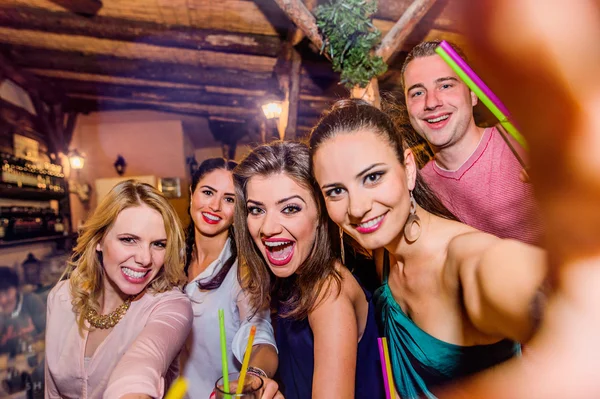 Young beautiful people with cocktails in bar taking selfie — Stock Photo, Image