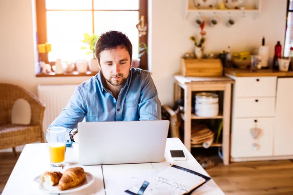 Man zit bij balie thuiswerken op laptop — Stockfoto