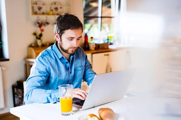 Mężczyzna siedzący przy biurku w pracy w domu na laptopie — Zdjęcie stockowe