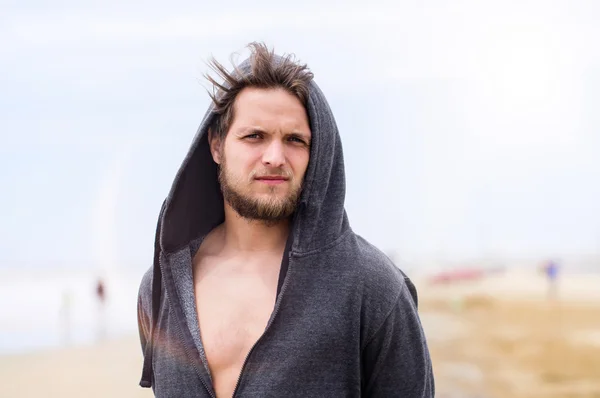 Hipster man on beach, wearing hooded sweatshirt, sunny summer — Stock Photo, Image