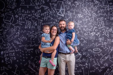 Young family with two little daughters against big blackboard