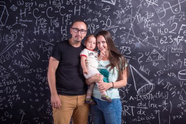 Young family with little daughter against big blackboard
