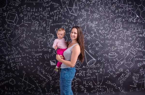 Young mother with little daughter against big blackboard — Stok fotoğraf