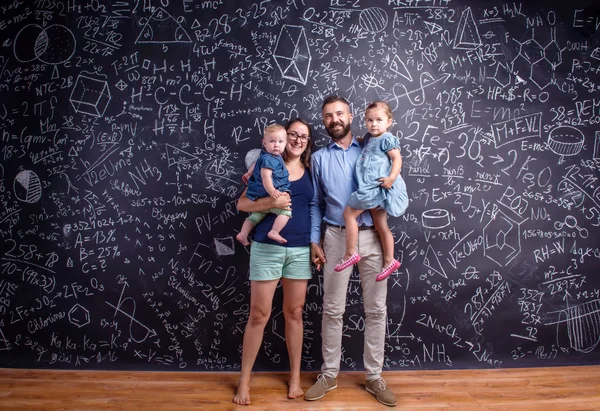Junge Familie mit zwei kleinen Töchtern gegen große Tafel — Stockfoto
