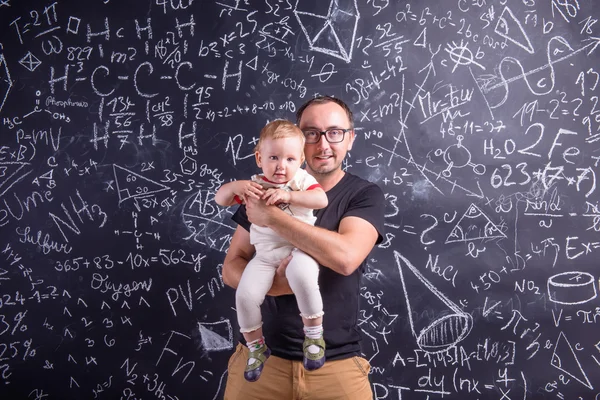 Young father with little daughter against big blackboard — Stock Photo, Image