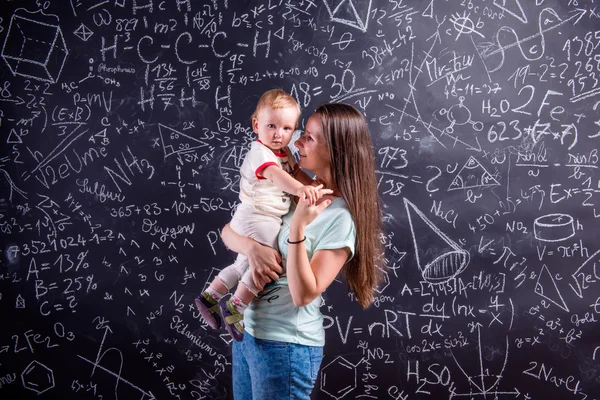 Young mother with little daughter against big blackboard — Zdjęcie stockowe