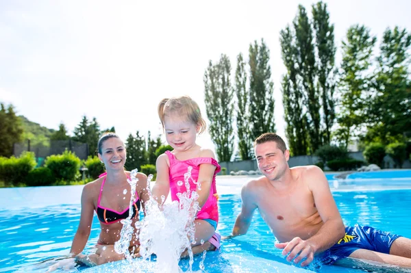 Madre, padre e hija en la piscina. Verano soleado . — Foto de Stock