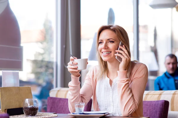 Жінка в кафе п'є каву, робить дзвінок — стокове фото