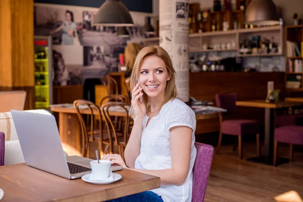 Kvinna i Café, talar i telefon, arbetar med anteckningsbok — Stockfoto