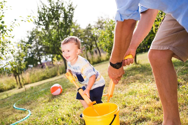 Malý chlapec s otcem hrál s vodní děla, šplouchání — Stock fotografie