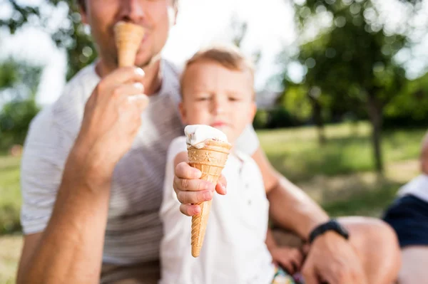 Ojciec i syn jedzą lody, słoneczny letni ogród — Zdjęcie stockowe