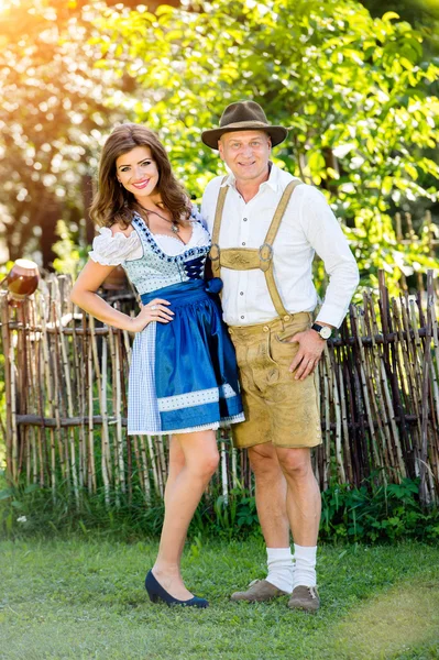 Coppia in abiti tradizionali bavaresi in piedi in giardino — Foto Stock