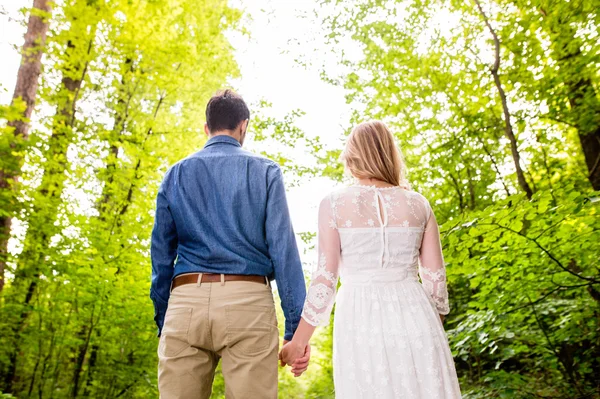 Beautiful wedding couple outside in green forest. Rear view. — Stock Photo, Image