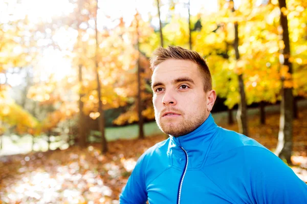 Jonge knappe hipster loper buiten in de zonnige herfst natuur — Stockfoto