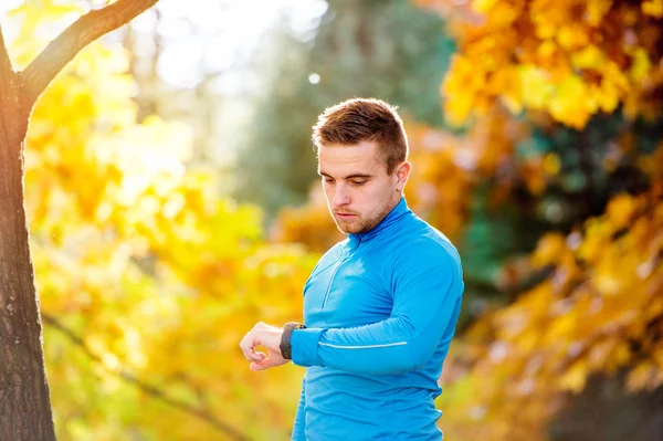 Runner in autumn nature measuring time with his watch — Stock Photo, Image