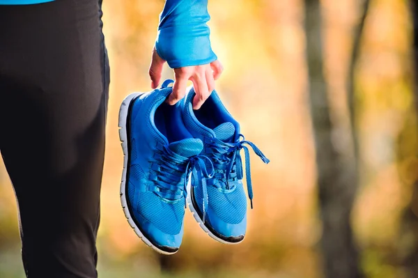 Corredor joven sosteniendo zapatos deportivos — Foto de Stock