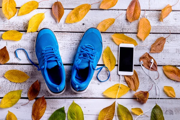 Sapatos desportivos. Smartphone, fones de ouvido, folhas — Fotografia de Stock