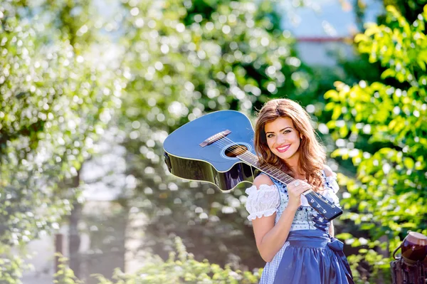 Женщина в баварском платье с гитарой — стоковое фото