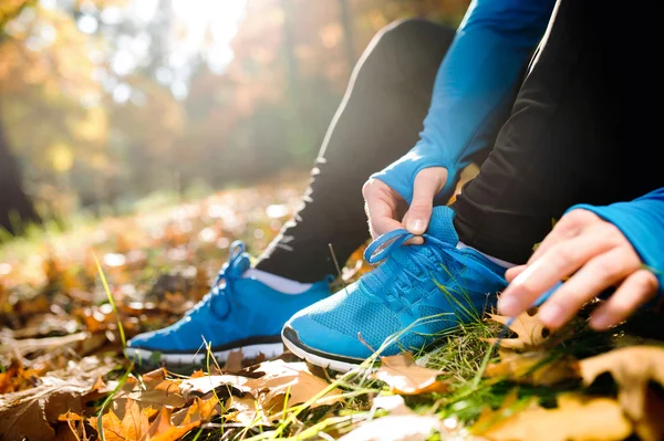 Loper zittend op de grond, koppelverkoop schoenveters — Stockfoto