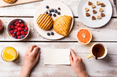Kahvaltı öğünde kağıt tutan kadın.