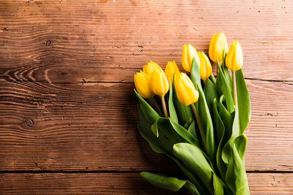 Bouquet of yellow tulips on wood