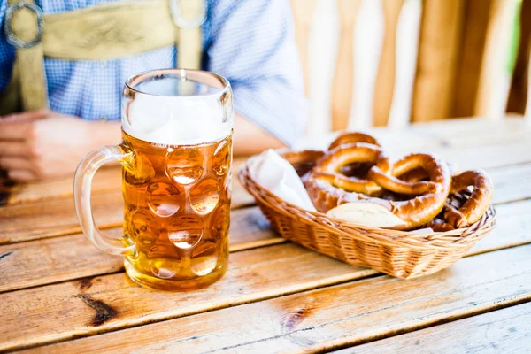 Hombre con ropa bavariana con cerveza y pretzels — Foto de Stock