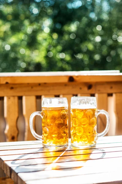 Dva džbány piva na dřevěném stole — Stock fotografie