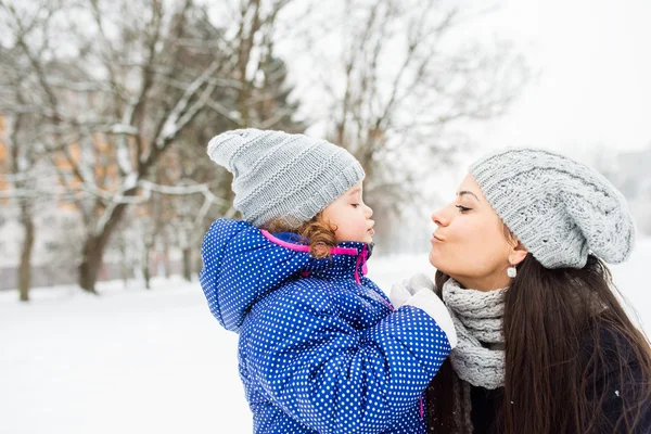 Moeder met haar dochter kussen buiten in de natuur van de winter — Stockfoto
