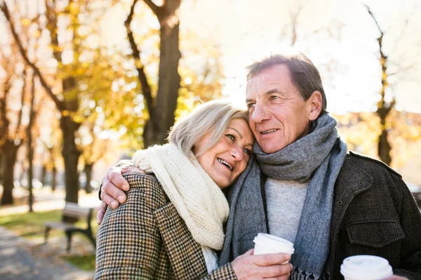 Vackra Senior par kramar i parken, dricka kaffe. Hösten — Stockfoto