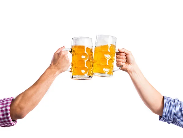 Two unrecognizable men clinking with beer mugs, studio shot — Stock Photo, Image