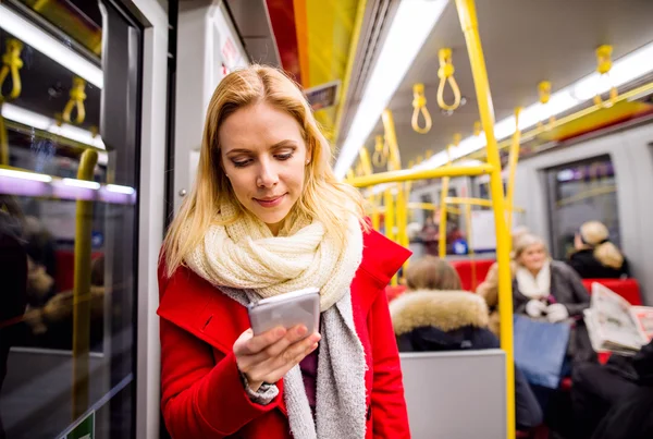 Hermosa mujer joven con teléfono inteligente en tren subterráneo —  Fotos de Stock