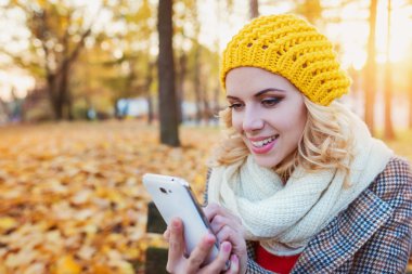 Güzel bir kadınla renkli sonbahar Park akıllı telefon