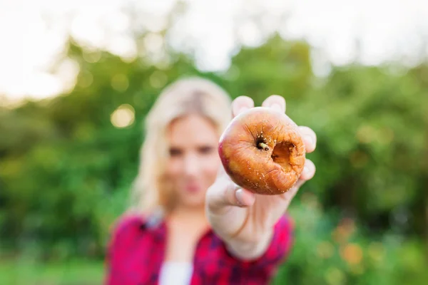 Unrecognizable blond woman holding rotten apple in her hand — Stock Photo, Image