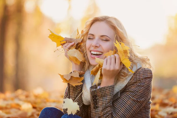 Vrouw in ingecheckte jas zitten in herfst park — Stockfoto