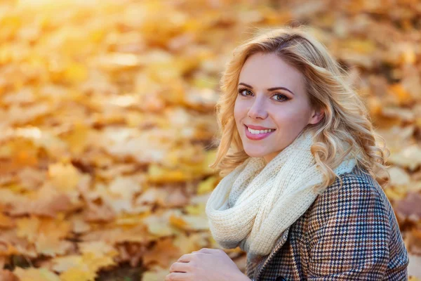 Vrouw in ingecheckte jas zitten in herfst park — Stockfoto