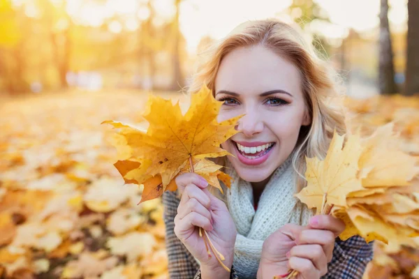 Woman in checked coat sitting in autumn park — Stock Photo, Image