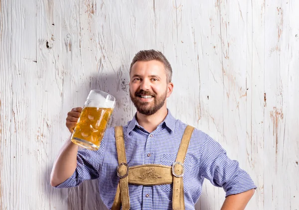 Человек в баварской одежде держит пиво — стоковое фото