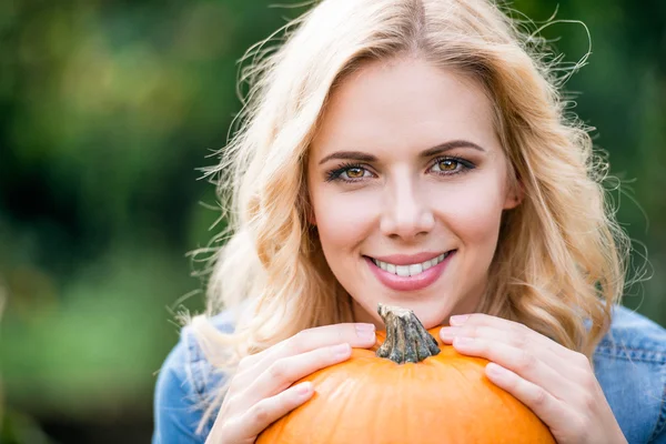 Vrouw bedrijf oranje pompoen — Stockfoto