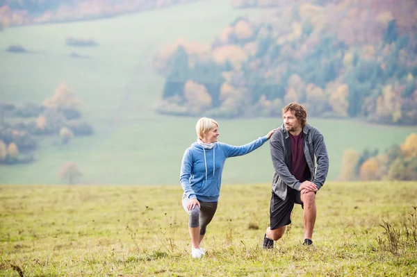 Två unga löpare stretching benen — Stockfoto